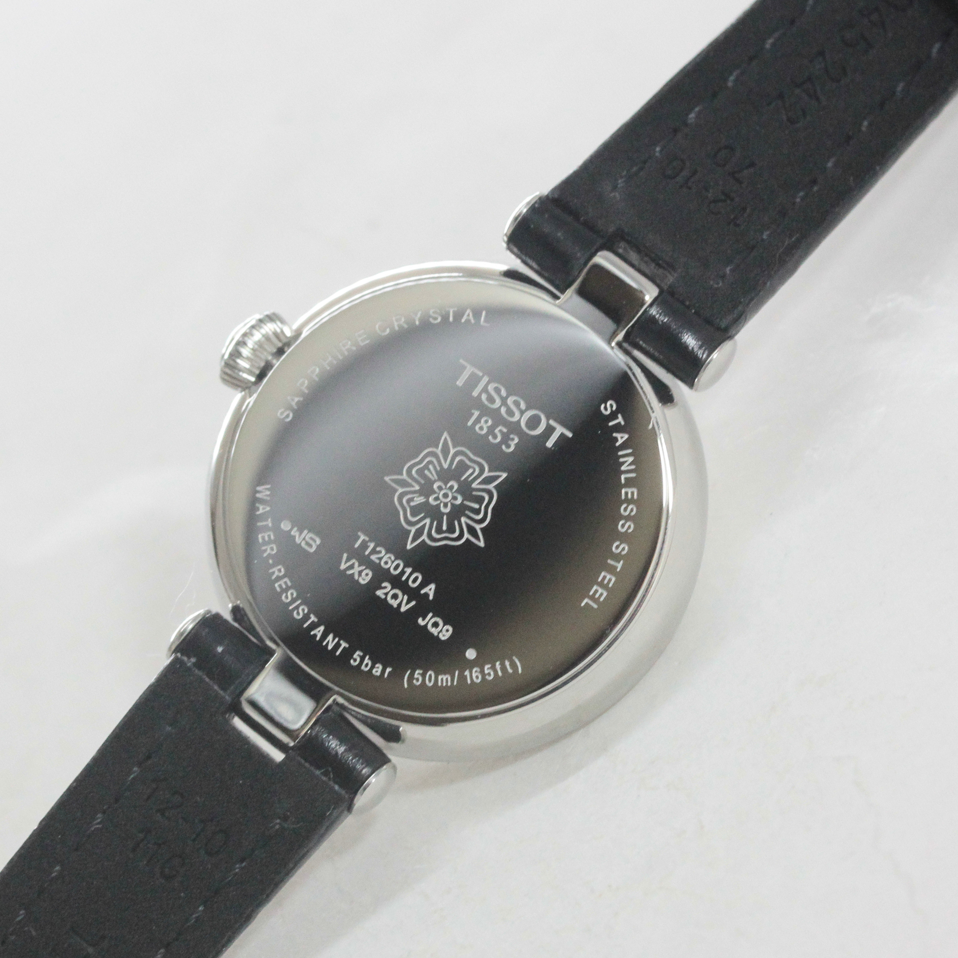 ケース本体裏側。ブランドロゴと、レディースウォッチに似合う花のイラストが刻印されています。