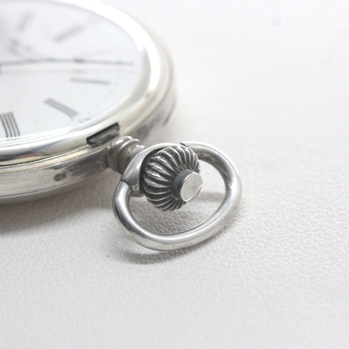 3時方向には蓋の開閉ボタンを備えた、ゼンマイの巻き上げと時刻調整を行うリューズ